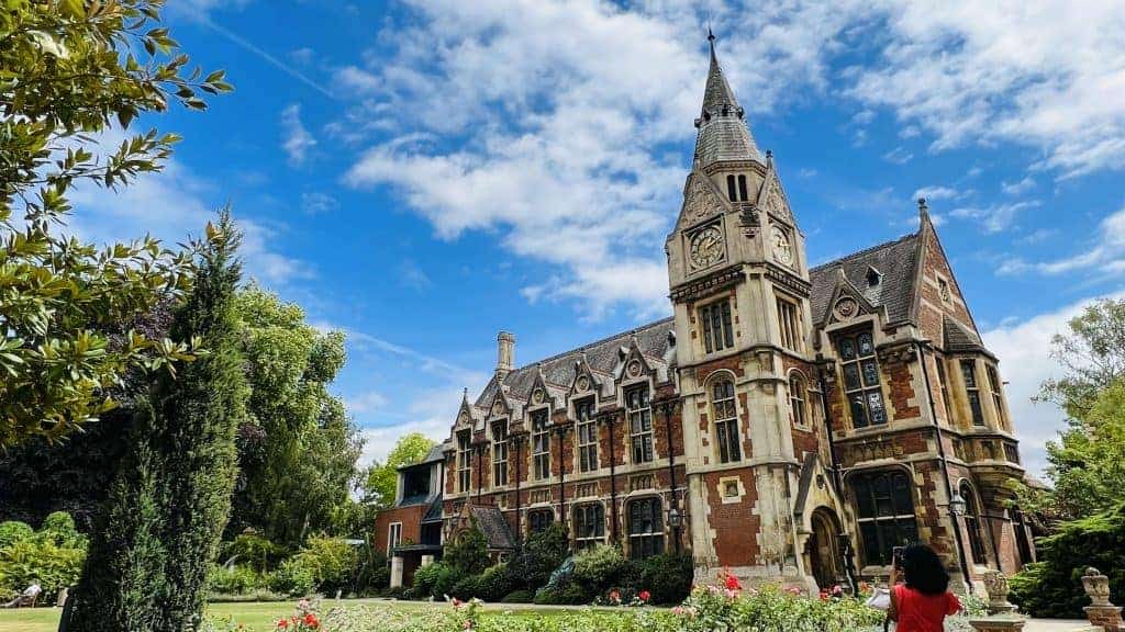 Edificio de ladrillo y piedra del Pembroke College con su torre, entre jardines