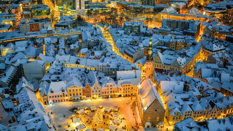 El casco viejo de Tallin nevado de noche, con la plaza del mercado iluminada