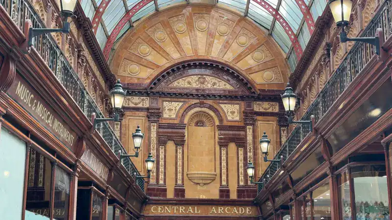 Interior de la Central Arcade de Newcastle, con mosaicos en el piso y vitrinas de madera