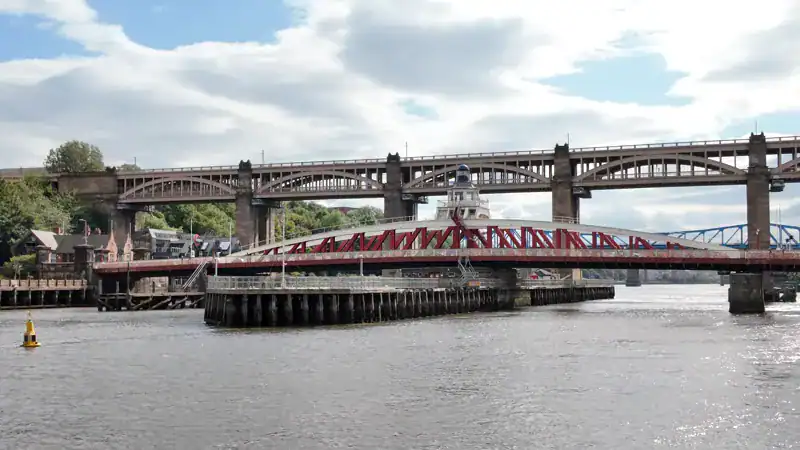 El Swing Bridge de Newcastle, rojo y bajo, con el High Level Bridge detrás