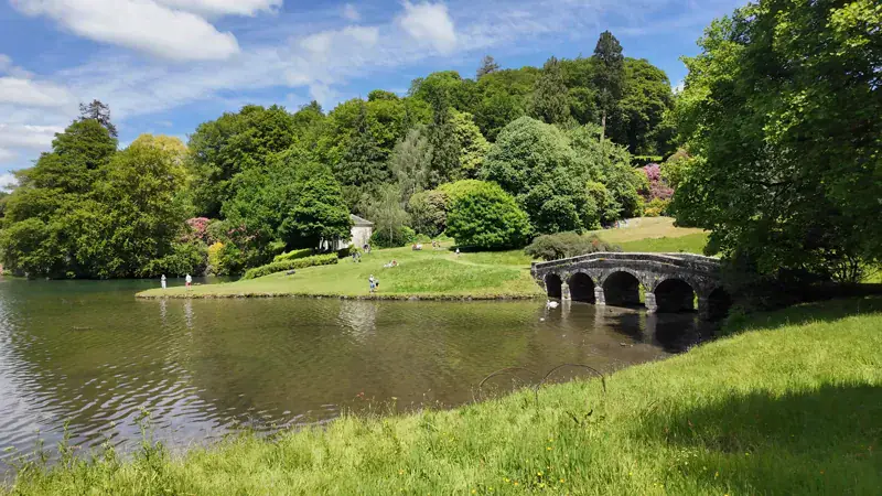 Lago y puente de piedra rodeados de árboles en los jardines de Stourhead